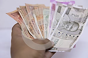 Hand holding Indian rupee notes against white