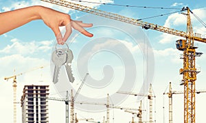 Hand holding keys on construction site background
