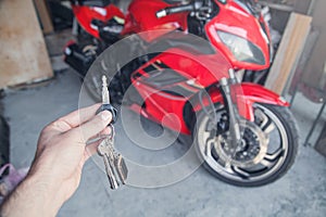 Hand holding a keys in the garage, on the background of motorcycle