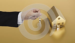 Hand holding keys with golden land and house background, real estate and property concept