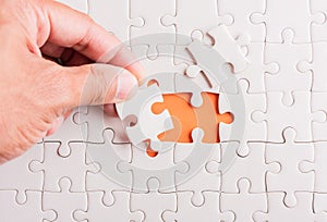 Hand-holding last piece white paper jigsaw puzzle game last pieces put to place