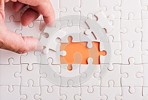 Hand-holding last piece white paper jigsaw puzzle game last pieces put to place