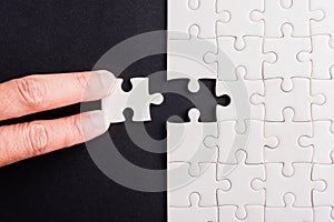Hand-holding last piece white paper jigsaw puzzle game last pieces put to place