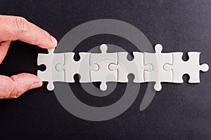 Hand-holding last six-piece white paper jigsaw puzzle
