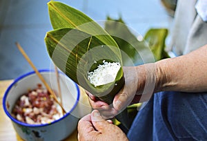 Hand Holding Leaf Filled by Sticky Rice. Pork Fillings Blurred at Background