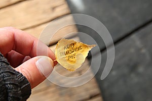 Hand holding leaf with text Happy Thanksgiving day