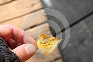 Hand holding leaf with text Happy Thanksgiving day