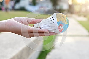 Hand is holding the LED bulb with nature background for save the earth concept
