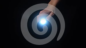 A hand holding a led flashlight with blue beam and shine in camera in the dark
