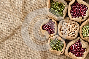 Hand holding legumes seed in sack bag put on linen cloth backgroundLegume seed in sack bag on linen fabric background, top view