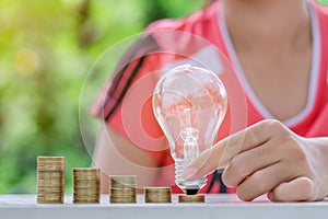Light bulb with Coins stack on wooden table in the morning. Energy and Money saving , accounting and financial concept