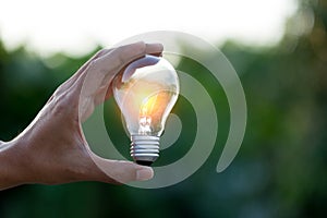 Hand holding light bulb,energy sources for renewable,natural energy concept