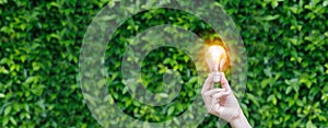 Hand holding Light bulb with light flare green nature background. eco innovation environmental and creative concepts.