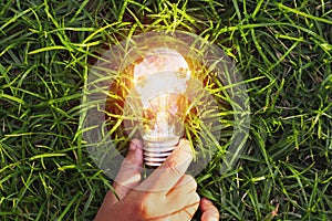 hand holding light bulb on grass. eco concept power energy in na