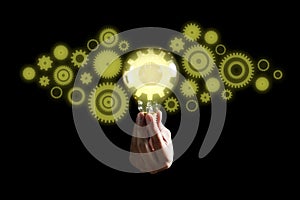 Hand holding light bulb and Innovation gears connection icon inside. Idea and inspiration on black background