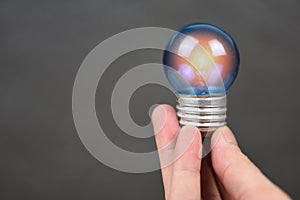 Hand holding light bulb with light from the lamp on black background - energy saving idea , power saving and the world concept
