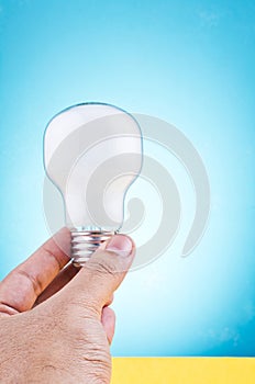 Hand holding light bulb over beautiful reverberation gradient background