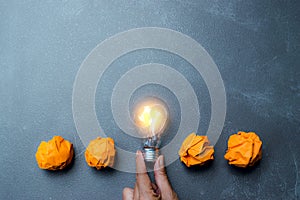 Hand holding light bulb put in the middle of orange papers it for idea,energy,solar concept.