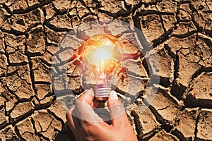 hand holding light bulb on soil arid. concept power solar energy