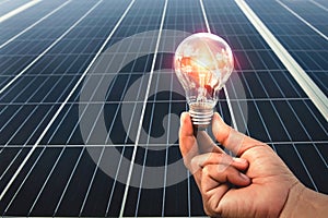 hand holding light bulb with solar panel background