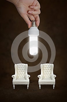 Hand holding a light bulb with vintage chair