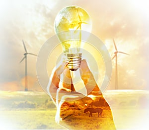 Hand holding light bulb on wind turbine