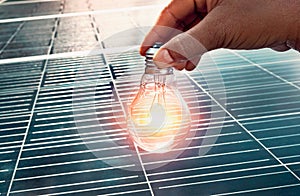 hand holding lightbulb on solar panel concept clean energy in nature