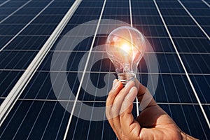 hand holding lightbulb on solar panel concept clean energy in nature