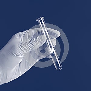 Hand holding liquid in test tube close up isolated on a blue background.