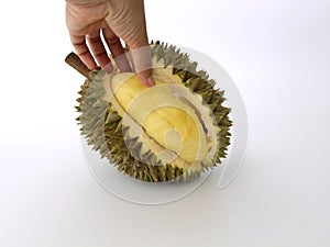 The hand is holding lobe of durian that has been partially peeled. photo