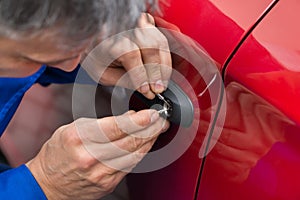 Hand Holding Lockpicker To Open Car Door