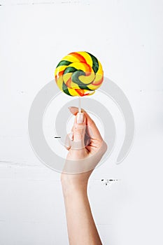 Hand holding lollipop isolated on white wood background photo