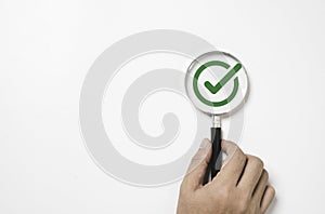 Hand holding magnifier glass with green correct sign or tick mark for document , project approve and accept verification code