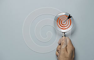 Hand holding magnify glass with red target board inside for focus and setup business objective target concept