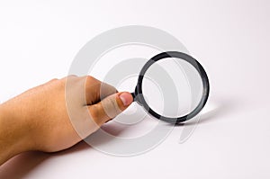 A hand is holding a magnifying glass against a white background. Find information and things, special search capabilities. photo