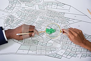 Hand Holding Magnifying Glass Over Cadastre Map