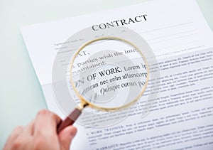 Hand holding magnifying glass over contract