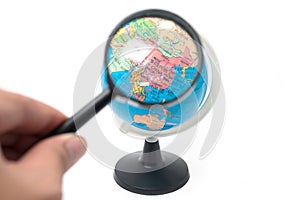 Hand holding magnifying glass over earth globe