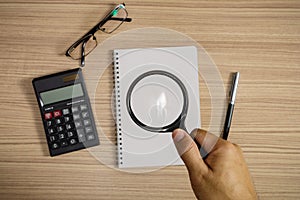 Hand Holding Magnifying Glass Over Notepad