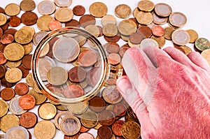 A hand is holding a magnifying glass over a pile of coins