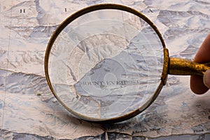 Hand holding magnifying glass showing map detail of Mt. Everest on a vintage topographical map photo
