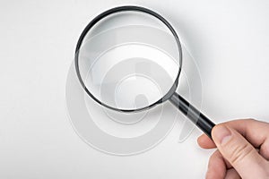 Hand holding magnifying glass  on white background. male hand holding black magnifying glass. Research, searching or