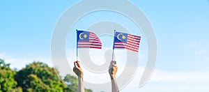 Hand holding Malaysia flag on blue sky background. September Malaysia national day and August Independence day