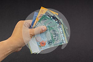 Hand holding Malaysia Ringgit MYR Currency Bank Notes.