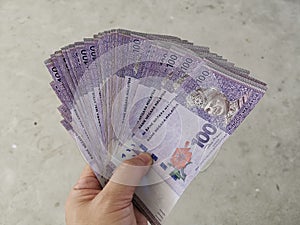 A hand holding Malaysian currency bank notes.