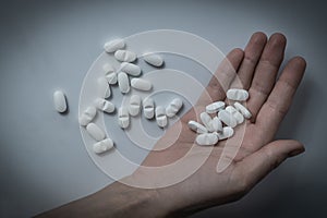 Hand holding many white prescription drugs, medicine tablets or vitamin pills in a pile - Concept of healthcare, opioids addiction