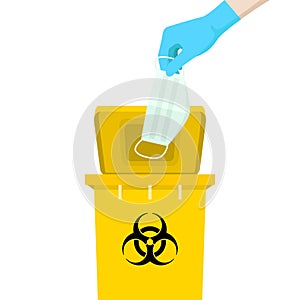 Hand holding a mask is above the yellow bin, with the symbol of infectious waste. How to discard the surgical mask correctly. photo