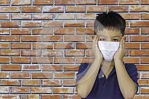 The hand holding the mask on Asian boy face background brick wall