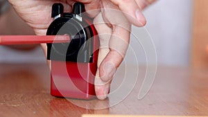 Hand holding mechanical pencil sharpener with colored pencil.