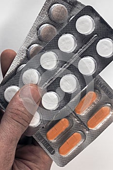 Hand holding medical drugs - full silver leaflet of white pills in common tablets shape, isolated on white background